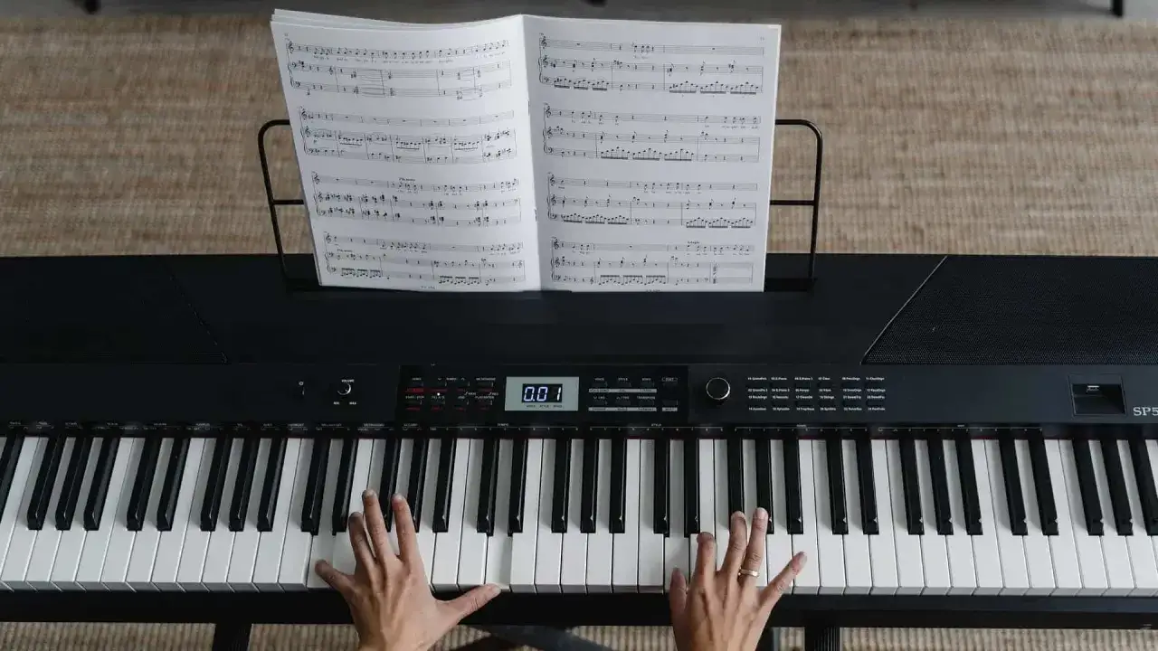 H&auml;nde, die auf einer Tastatur spielen, Noten auf einem Notenst&auml;nder.