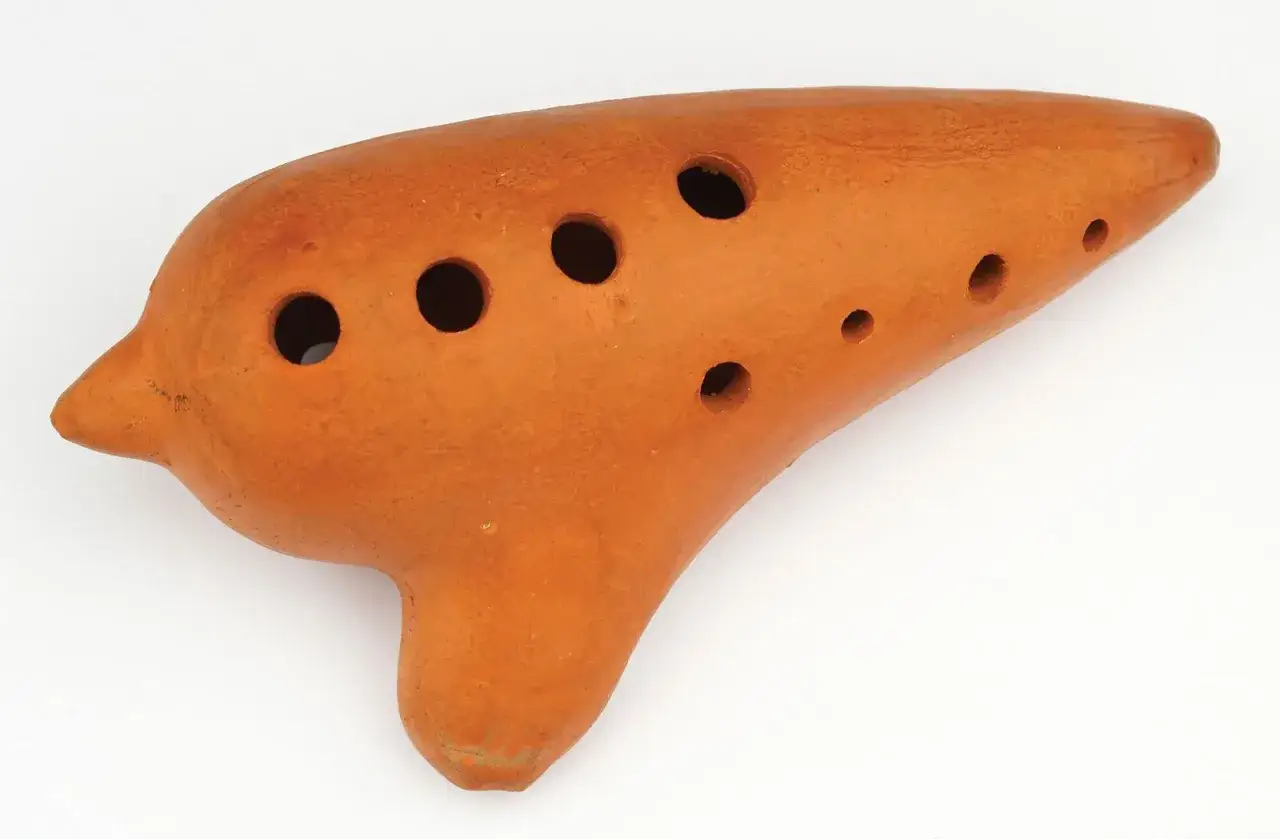 Orangefarbenes, tonartiges Musikinstrument mit vielen L&ouml;chern, das an eine Okarina erinnert.